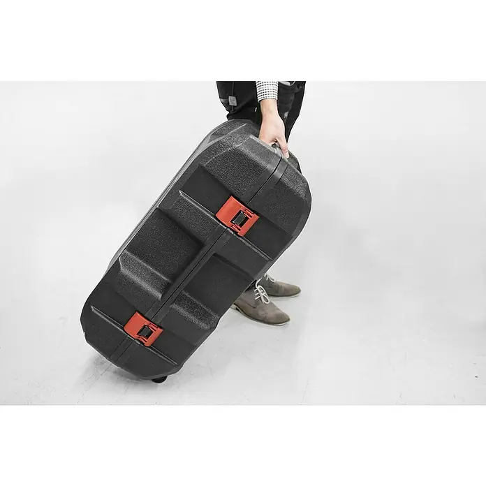 Güde Benzin-Pfahlramme GPR 801 E - 1 kW - Eine Person trägt einen robusten schwarzen Instrumentenkoffer mit roten Verschlüssen. Ideal für den sicheren Transport empfindlicher Ausrüstung.