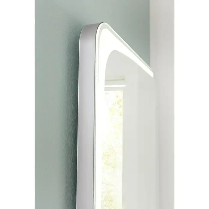 Camargue Faro Mini LED-Lichtspiegel - 55 x 80 cm - Nahaufnahme eines eleganten LED-Badezimmerspiegels mit abgerundeten Ecken und reflektierendem Fensterblick für moderne Badezimmerästhetik.