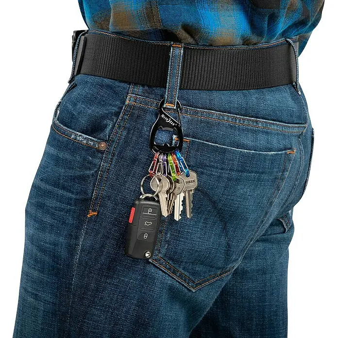 Nite Ize Schlüsselanhänger - Länge: 90 mm - Nahaufnahme einer Person in Jeans mit einem Nite Ize Karabiner-Schlüsselanhänger, der am Gürtel befestigt ist, mit Schlüsseln.
