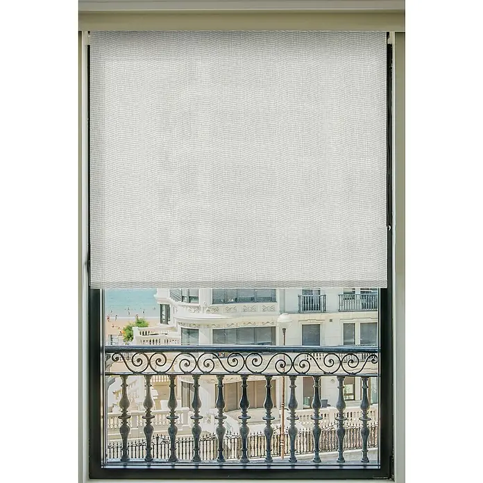 Estor enrollable Montreal - An x Al: 105 x 250 cm, Blanco - Primer plano de una ventana con un estor gris parcialmente subido, revelando una vista exterior de edificios y un balcón.