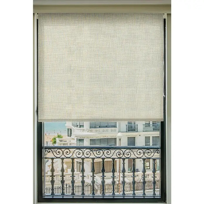 Estor enrollable Aspen - An x Al: 165 x 250 cm, Crudo - Vista a través de una ventana con un estor beige parcialmente bajado, que da a un balcón y una ciudad costera.