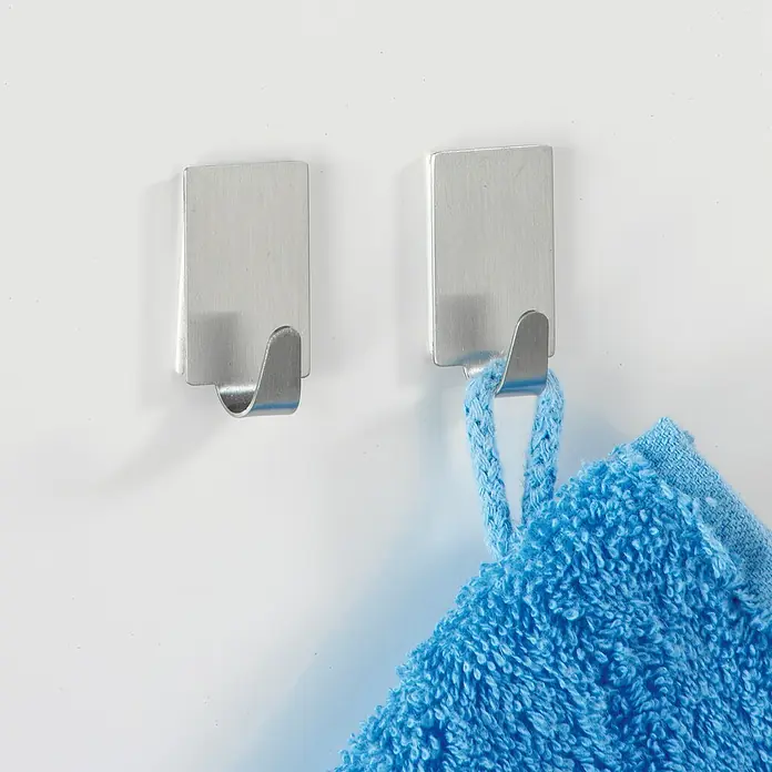 Wenko Handtuchhaken - L x B x H: 3,4 x 1,9 x 1,5 cm, 4 Stk., Edelstahl, Matt - Zwei silberne Wandhaken, einer mit blauem Handtuch. Die Haken sind schlicht und modern gestaltet, ideal für Bad oder Küche.