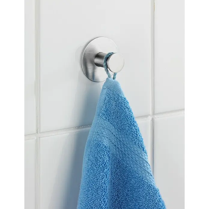 Wenko Handtuchhaken Celano - 1 Stk., Edelstahl, Matt - Nahaufnahme eines blauen Handtuchs, das an einem modernen, runden Wandhaken aus gebürstetem Stahl in einem Badezimmer hängt.