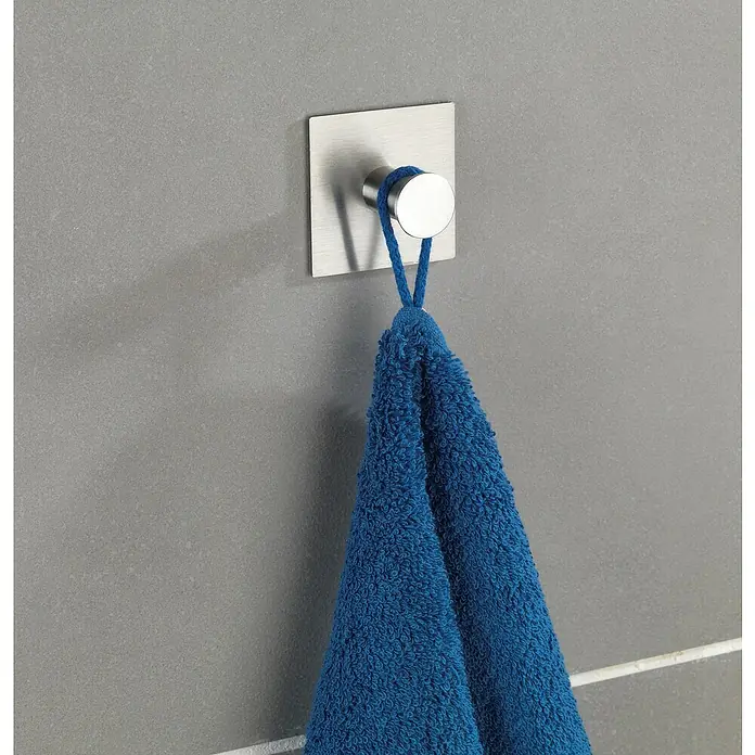 Wenko Handtuchhaken Accadia - 1 Stk., Edelstahl, Matt - Handtuch hängt an einem silbernen, quadratischen Handtuchhaken an einer grauen Wand.