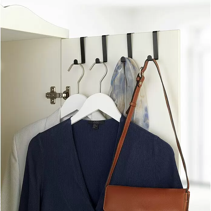 Wenko Türhaken - 4 Stk., Metall, Schwarz - Schwarze Türhaken an einer Schranktür halten zwei weiße Kleiderbügel mit Kleidung, einem gemusterten Schal und einer braunen Ledertasche.