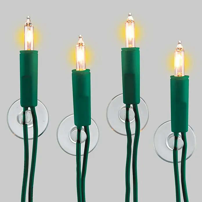 Wenko Saugnapf-Haken - 6 Stk., Kunststoff, Transparent - Nahaufnahme von vier warm leuchtenden Lichterketten mit grünen Kabeln, befestigt mit Saugnäpfen auf grauem Hintergrund.