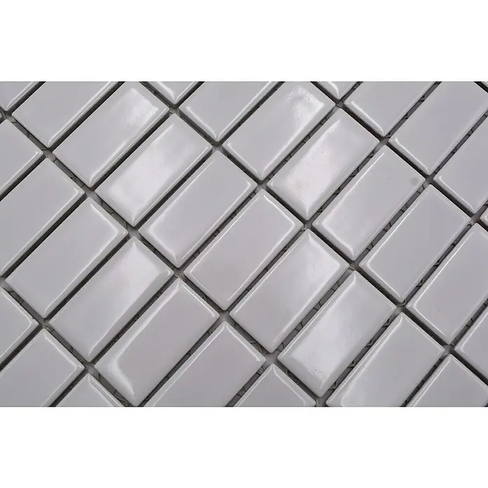 Mosaikfliese Stäbchen Uni ST 370 - 29,8 x 29,8 cm, Weiß, Glänzend - Nahaufnahme der hellgrauen Keramikfliesen, die in einem Fischgrätenmuster angeordnet sind und eine glänzende Oberfläche aufweisen.