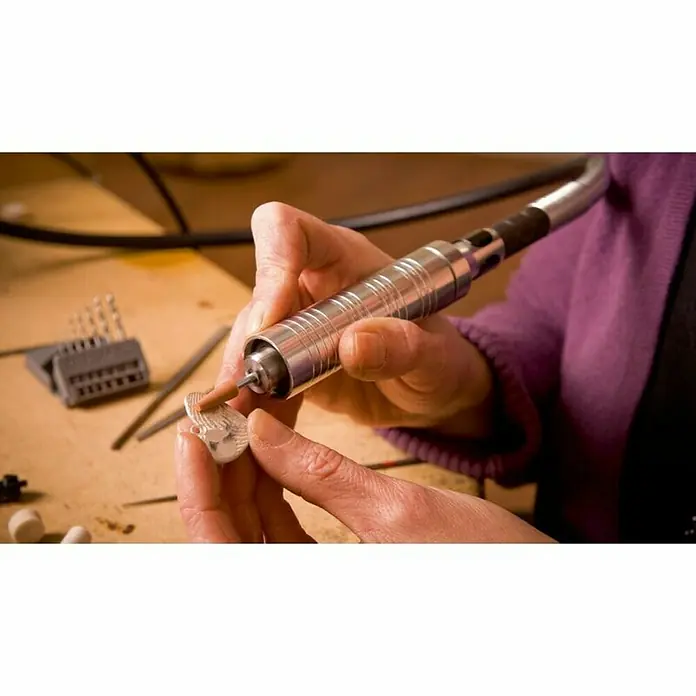 Dremel Fortiflex Herramienta rotativa eléctrica Fortiflex 9100-21 - Número de revoluciones de marcha en vacío: 20.000 r.p.m. - Primer plano de un artesano que utiliza una herramienta rotativa Dremel para refinar una joya delicada. Centrado en la precisión y el trabajo detallado.
