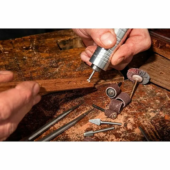Dremel Fortiflex Herramienta rotativa eléctrica Fortiflex 9100-21 - Número de revoluciones de marcha en vacío: 20.000 r.p.m. - Una imagen detallada de una persona que usa una herramienta Dremel en una pieza de madera, rodeada de varios accesorios para carpintería.