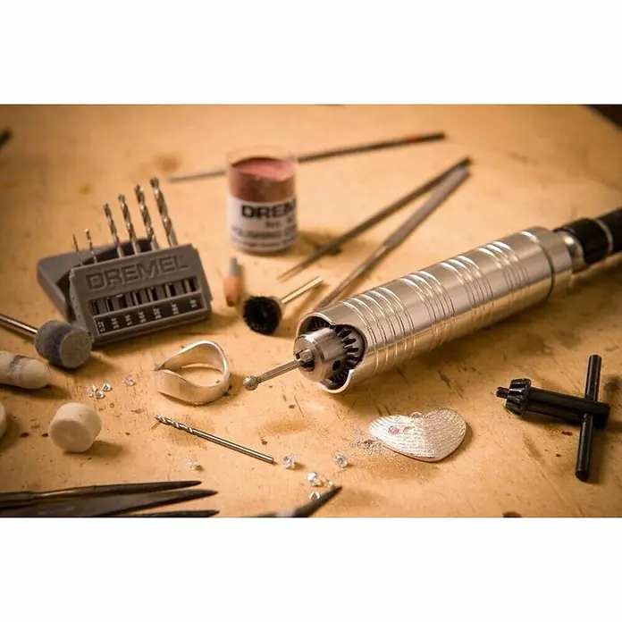 Dremel Fortiflex Herramienta rotativa eléctrica Fortiflex 9100-21 - Número de revoluciones de marcha en vacío: 20.000 r.p.m. - Primer plano de una herramienta rotativa Dremel con accesorios en un banco de trabajo, ideal para joyería y artesanía detallada.