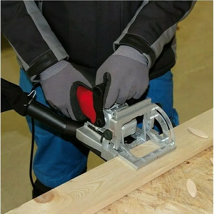 Einhell Engalletadora TC-BJ900 - 860 W, Profundidad de fresado: 14 mm - Una persona que utiliza una ensambladora de galletas en una tabla de madera para crear una ranura limpia para las uniones de madera.