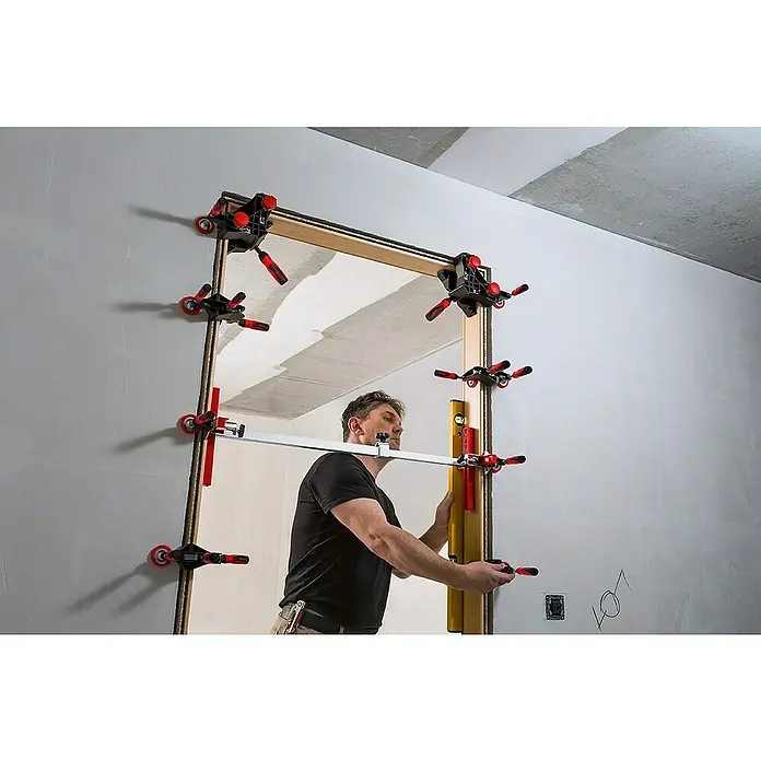 Bessey Richtzwinge TFM - Ausladung: 70 mm - Ein Mann montiert mit einem Türfuttermontageset eine Türzarge. Das Set besteht aus Spannzwingen und Justierelementen für präzise Ergebnisse.