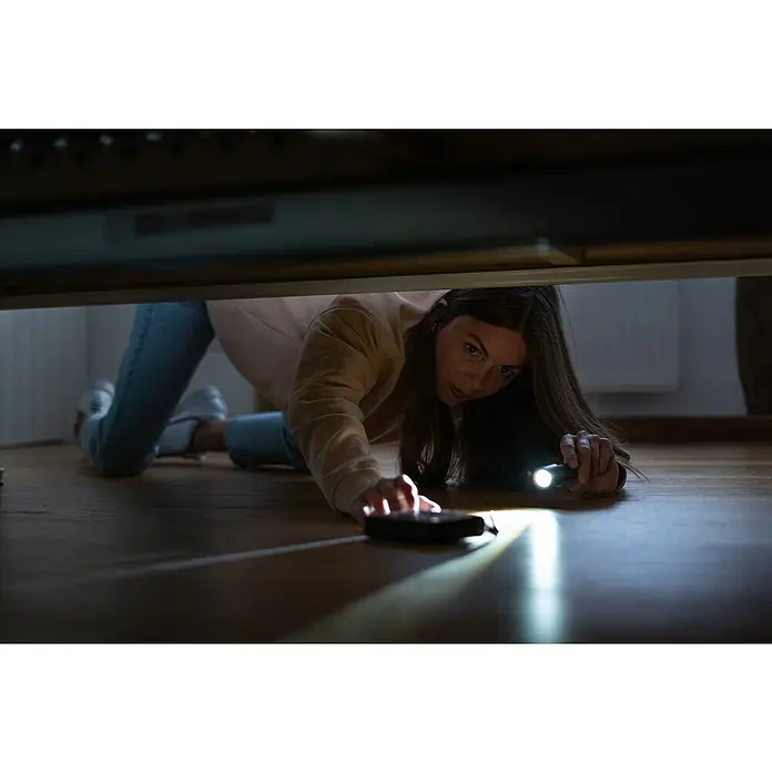Ledlenser Taschenlampe P5R Core - 15 lm - 500 lm, IP68 - Eine Frau sucht mit einer Taschenlampe unter dem Bett nach einem verlorenen Gegenstand, vielleicht ein Handy oder eine Fernbedienung.
