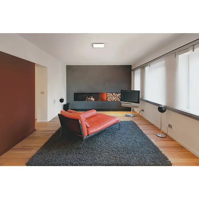 Ledvance Smart+ WiFi LED-Panel Planon Plus - L x B x H: 300 x 300 x 56 mm, Weiß, Warmweiß - Modernes Wohnzimmer mit rotem Sofa, dunklem Teppich, TV und Kamin. Die minimalistische Einrichtung wird durch die Holzelemente aufgelockert.