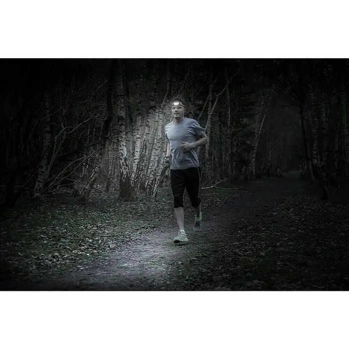 Energizer Linterna frontal deporte - 36 x 190 x 146 mm, 125 lm - Hombre corriendo en la oscuridad con una linterna frontal que ilumina el camino. La linterna frontal asegura una buena visibilidad para las carreras nocturnas en el bosque.