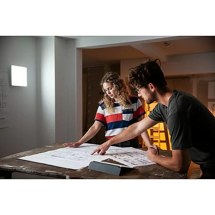 Ledvance Smart+ WiFi LED-Panel Planon Frameless - 36 W, L x B x H: 30 x 30 x 6,9 cm, Weiß, RGBW - Zwei Personen prüfen Baupläne auf einem Tisch und planen ein Projekt.