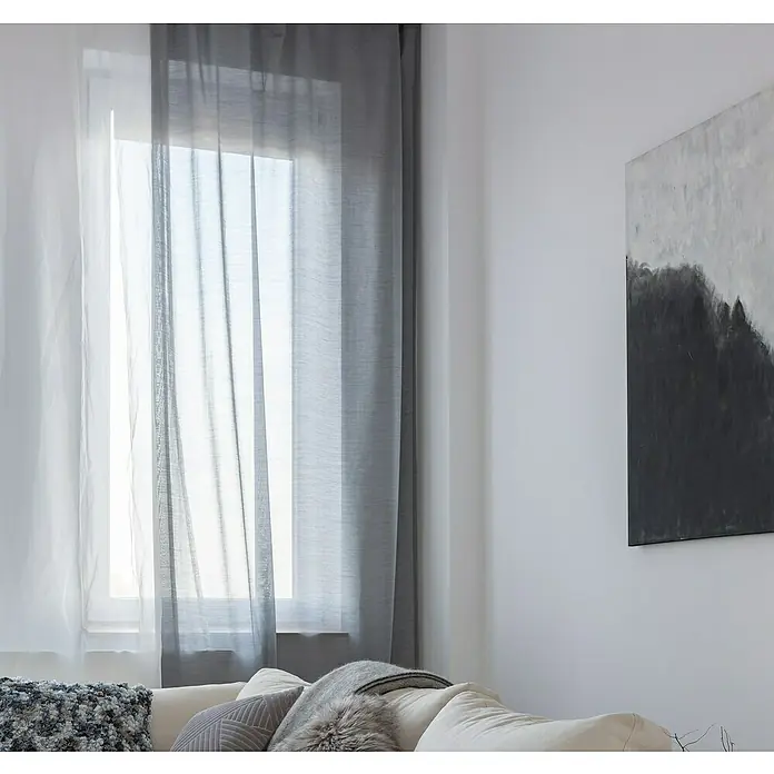 Cortina con ollaos Linum - An x Al: 280 x 300 cm, Gris - Vista a través de las cortinas blancas y grises translúcidas que adornan una ventana, creando un ambiente elegante y aireado en la habitación.