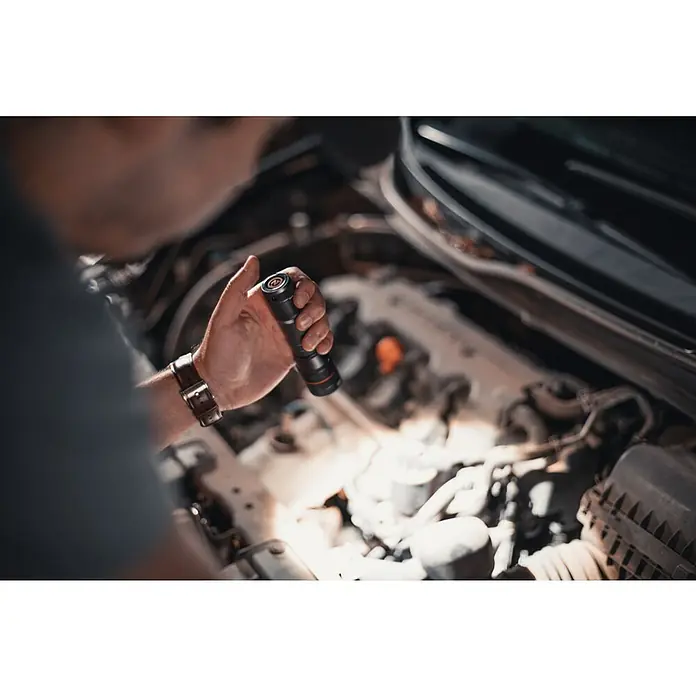 Nebo Tools Linterna táctil Newton - 3,51 x 3,18 x 13,34 cm, 500 lm, IP67 - Primer plano de una persona que utiliza una linterna brillante para inspeccionar el compartimento del motor de un coche.