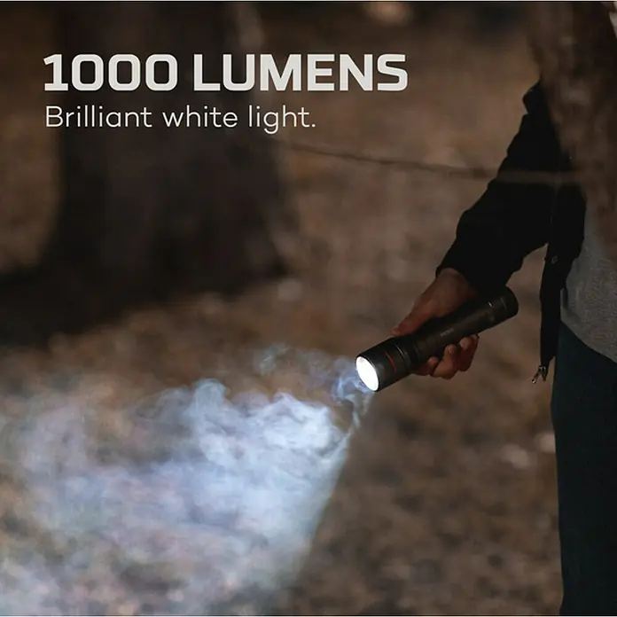 Nebo Tools Linterna táctil Newton - 3,81 x 4,78 x 17,78 cm, 1.000 lm, IP67 - Una persona sostiene una linterna Husky que emite 1000 lúmenes de luz blanca brillante, ideal para uso nocturno al aire libre.