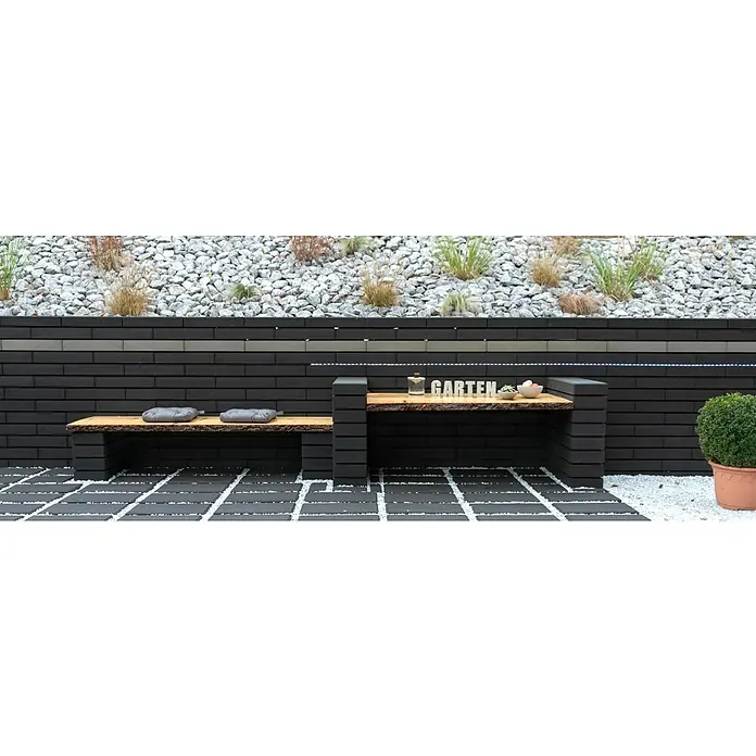 Christoph Mauerabdeckplatte C-Line - 50 x 25 x 8,5 cm, Anthrazit, Beton - Gartengestaltung mit einer Bank und einem Tisch aus dunklen Ziegelsteinen und einer rustikalen Holzplatte, dekoriert mit "Garten"-Schriftzug.