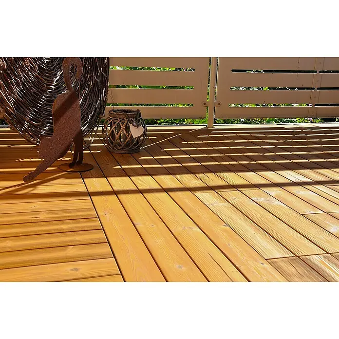 Loseta con sistema click Smartdeck - Pino, 30 x 30 x 2,5 cm, Natural, 6 ud. - Una zona rústica de cubierta de madera con una estatua de gato de metal decorativa, una cesta tejida y una linterna, creando un ambiente cálido y acogedor.