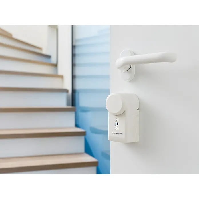 Homematic IP Funk-Türschlossantrieb HmIP-DLD - Weiß, Batteriebetrieben, 36 x 56 x 118 mm - Nahaufnahme einer Homematic IP Türschlossantrieb-Lösung an einer weißen Tür, mit Treppe im Hintergrund.
