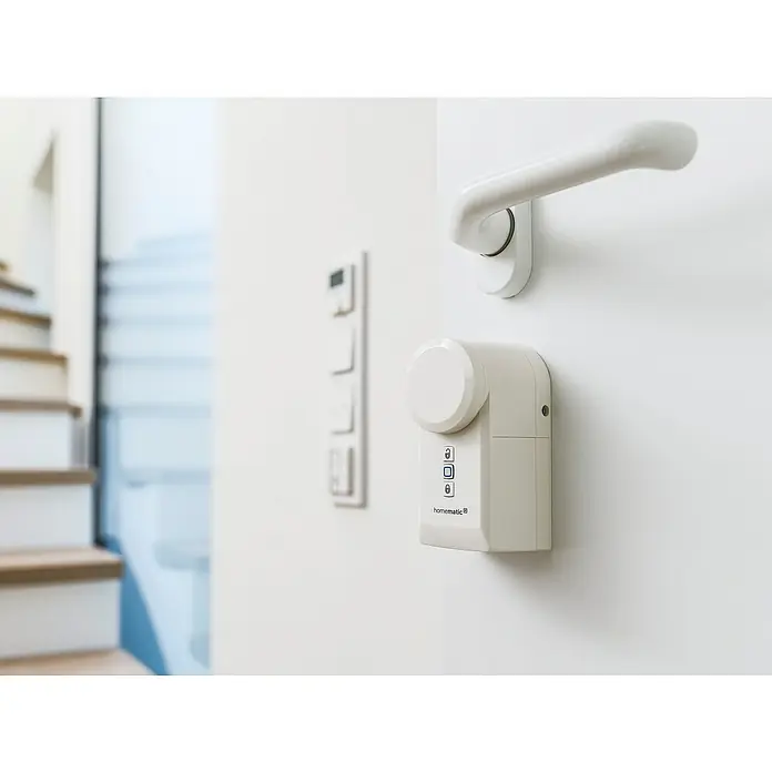 Homematic IP Funk-Türschlossantrieb HmIP-DLD - Weiß, Batteriebetrieben, 36 x 56 x 118 mm - Nahaufnahme eines Homematic IP-Türschlossantriebs mit Bedienelementen und einem weißen Türgriff auf einer weißen Tür.