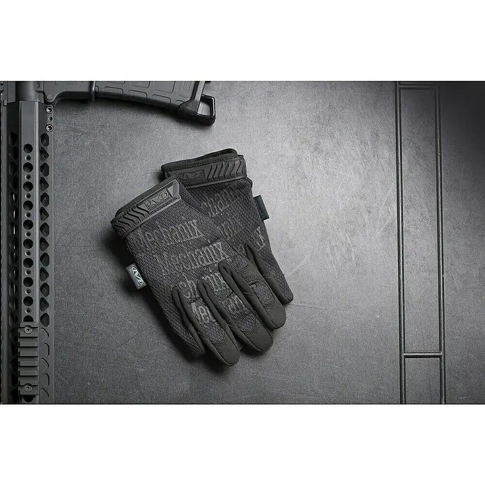 Mechanix Wear Arbeitshandschuhe The Original® Covert - L, Schwarz - Detailaufnahme von Mechanix Wear Tactical Spezialhandschuhen mit einem Gewehrlauf und Magazin auf dunklem Untergrund.