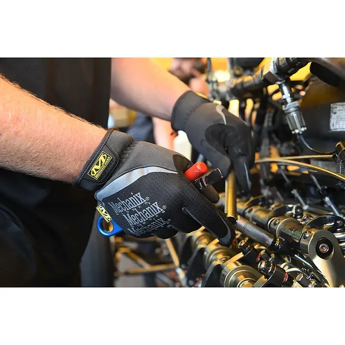 Mechanix Wear Arbeitshandschuhe FastFit - XL, Schwarz - Detailaufnahme eines Mechanikers mit Mechanix Wear Handschuhen, der an einem Motor arbeitet. Perfekt für sicheren Halt.