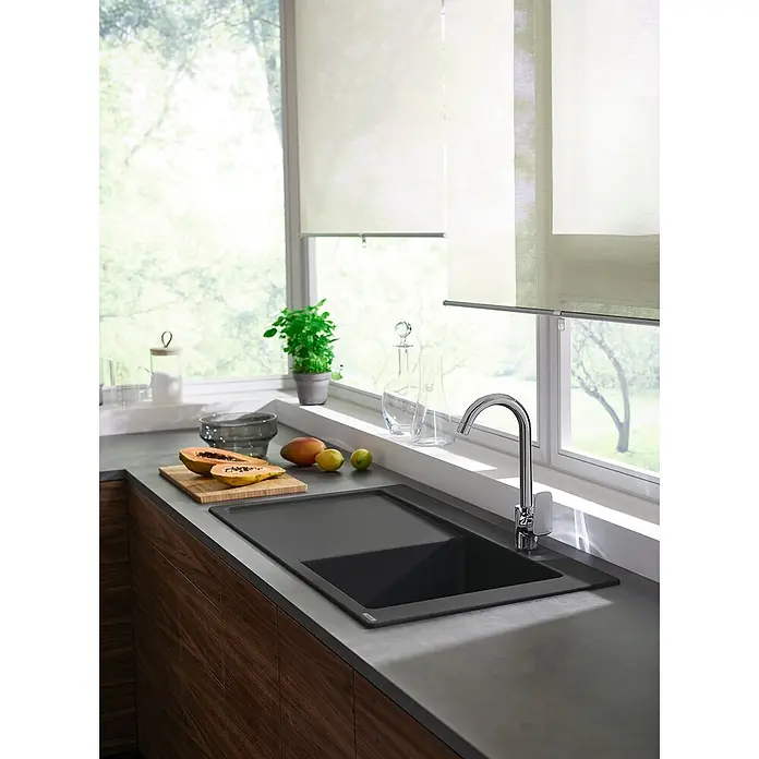 Hansgrohe Fregadero encastrable S5110 - F450 1S 1E - 105 x 51 cm, Grafito, Posición del estante: Derecha - Primer plano de un moderno fregadero de cocina negro situado frente a una ventana, con fruta en una tabla de cortar.