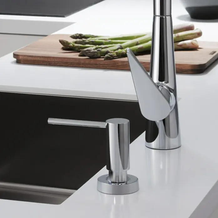 Hansgrohe Schaumsprüher - Chrom - Elegantes Spülbecken mit schlankem Wasserhahn und Seifenspender aus Chrom, ergänzt durch frischen Spargel auf einem Holzbrett.
