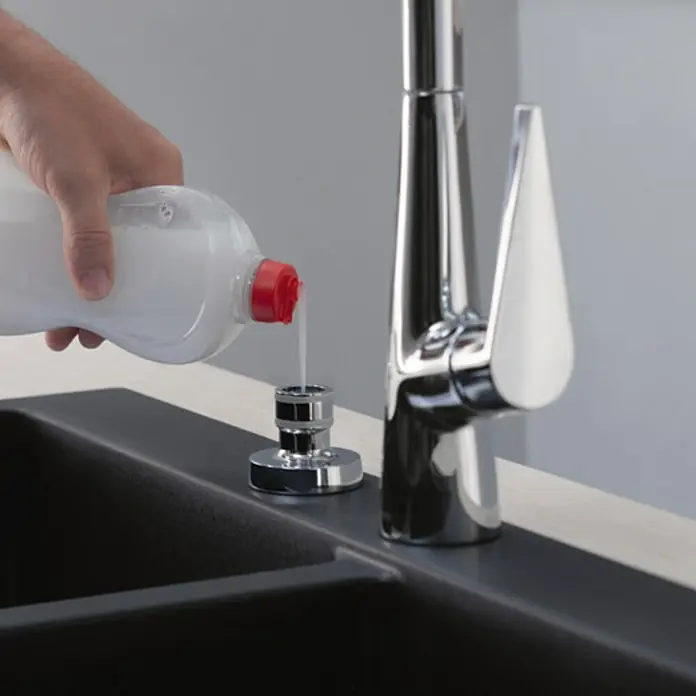 Hansgrohe Schaumsprüher - Chrom - Eine Hand füllt Spülmittel in einen eingebauten Seifenspender neben einem modernen Wasserhahn. Praktische Küchenlösung für saubere Hände.