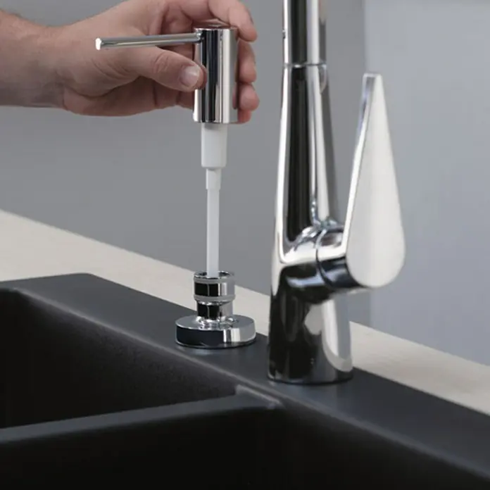 Hansgrohe Schaumsprüher - Chrom - Bild einer polierten Chrom-Spülmittelpumpe, die in einer modernen Küche neben einem eleganten Wasserhahn installiert ist.