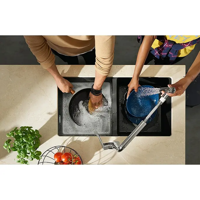 Hansgrohe Fregadero encastrable S510 - U770 2S - 45 x 82 cm, Piedra natural, Número de cubetas: 2 ud., Grafito, Resplandeciente - Fregadero con grifo: Dos personas lavan los platos en un moderno fregadero negro BLANCO con un elegante grifo sobre una encimera brillante.