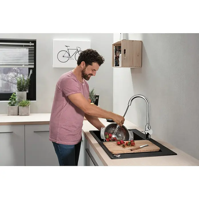 Hansgrohe Grifo de cocina Focus M43 - Caño alto, Cromo, Brillante - Un hombre lava fresas en un colador de cocina BLANCO bajo un moderno grifo BLANCO en una cocina elegante.