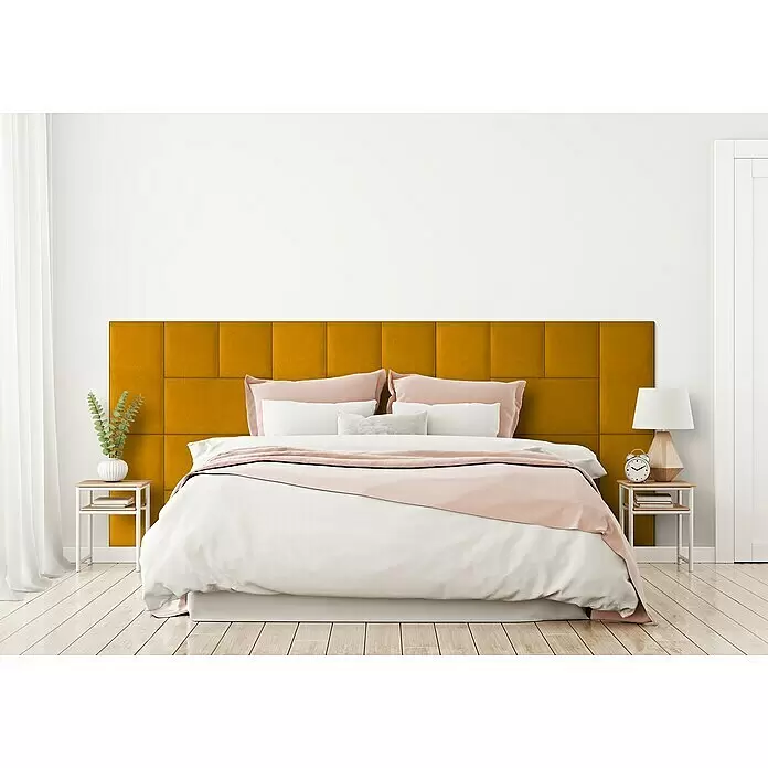 Fllow Wandpolster-Set Velvet A2 - 300 x 120 cm, Ocker - Ein modernes Bett mit großem gelben Polsterkopfteil, weißer Bettdecke und pinker Decke in einem hellen Schlafzimmer.