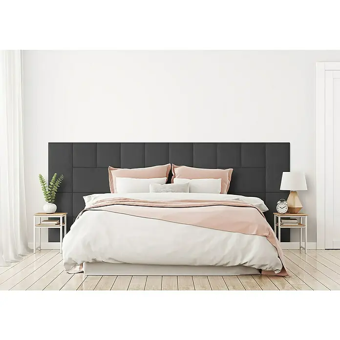 Fllow Wandpolster-Set Velvet A2 - 300 x 120 cm, Anthrazit - Ein elegantes Schlafzimmer mit einem Kingsize-Bett, einem schwarzen Kopfteil und rosafarbenen Akzenten. Die Nachttische sind aus hellem Holz mit weißen Rahmen.