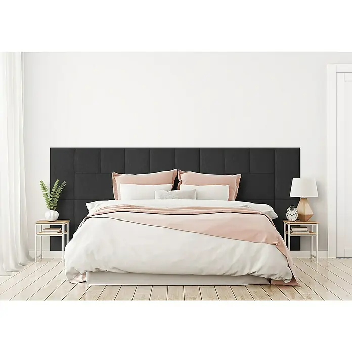 Fllow Wandpolster-Set Inari A2 - 300 x 120 cm, Anthrazit - Schlafzimmer-Interieur mit einem modernen Bett mit einem dunklen Kopfteil, weißen Bettbezug und rosa Akzenten, flankiert von Nachttischen mit Dekor.