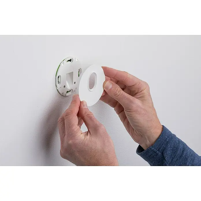 Paulmann LED-Einbauleuchte rund - 2,7 W, Weiß, L x B: 7,8 x 7,8 cm, Rund - Die Hände einer Person bringen eine kreisförmige Smart Home-Geräteabdeckung an einer Wand an.