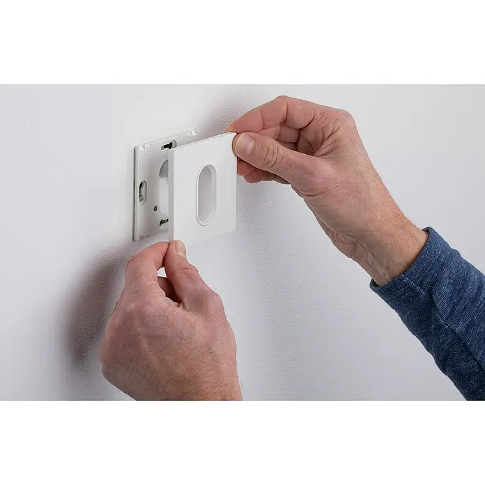 Paulmann LED-Einbauleuchte eckig - 2,7 W, Weiß, L x B: 7,8 x 7,8 cm, Eckig - Nahaufnahme eines Mannes, der eine quadratische, weiße Wandplatte mit einer ovalen Aussparung an einer Wandhalterung befestigt.