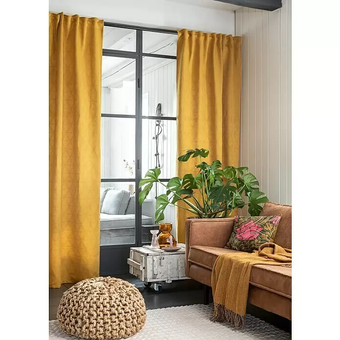 Elbersdrucke Schlaufenschal Sunny - B x H: 140 x 255 cm, 100% Polyester, Gelb - Goldgelbe Vorhänge mit dezentem geometrischem Muster rahmen ein Fenster in einem gemütlichen Wohnzimmer ein.