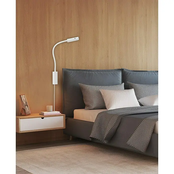 Fischer & Honsel Wandleuchte Raik - 5 W, Weiß/Gold - Eine moderne Wandleuchte aus Metall neben einem stilvollen Bett mit Nachttisch, die eine gemütliche Atmosphäre schafft.