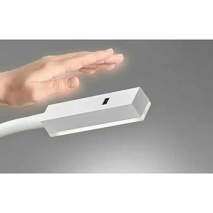 Fischer & Honsel Wandleuchte Raik - 5 W, Weiß/Gold - Nahaufnahme einer Hand, die sich einer modernen, weißen Schreibtischlampe nähert, um sie mit einer Geste zu bedienen.