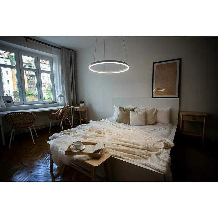 Direct Signs LED-Pendelleuchte Noble - Durchmesser: 800 mm, Weiß - Helle Schlafzimmeransicht mit einem modernen kreisförmigen LED-Kronleuchter, der über einem Bett mit weichen Kissen und Decken hängt.