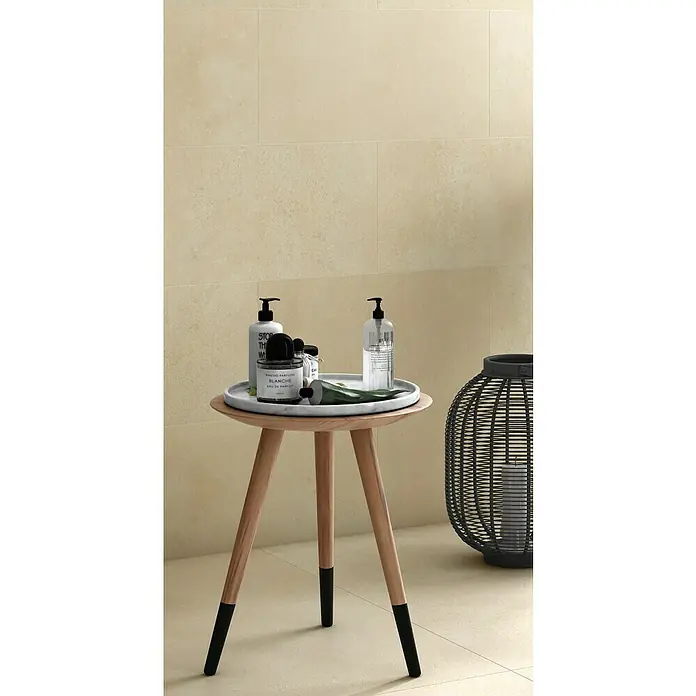 Art-Tec by Palazzo Feinsteinzeugfliese - 30 x 60 cm, Creme, Matt - Dekoratives Badezimmerstillleben mit Pflegeprodukten auf einem Beistelltisch mit Kerzenlaterne und beige Fliesen.