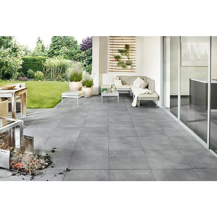 Art-Tec by Palazzo Terrassenfliese - 60 x 60 x 2 cm, Steel, Matt - Bild eines Außenbereichs mit großen grauen Fliesen, Gartenmöbeln und einem Holzkohlegrill, der Rauch erzeugt, was eine einladende Atmosphäre schafft.