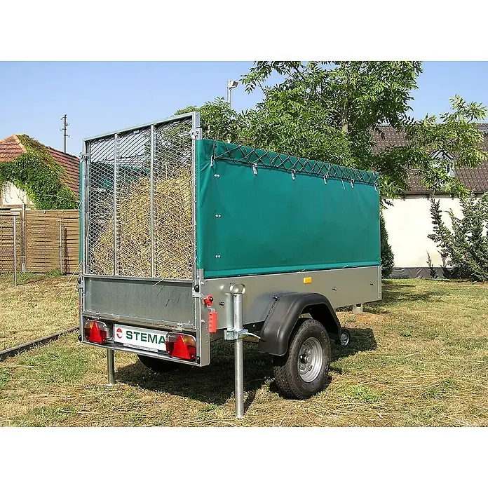Stema Anhänger Green Keeper 750 mit Hochplane - Nutzlast: 588 kg, Einachser, Kasteninnenmaß: 201 x 108 x 26,5 cm, Ungebremst - Ein Stema Anhänger mit grüner Plane und Gitteraufsatz steht auf einer Wiese. Die Ladefläche ist mit Stroh gefüllt.