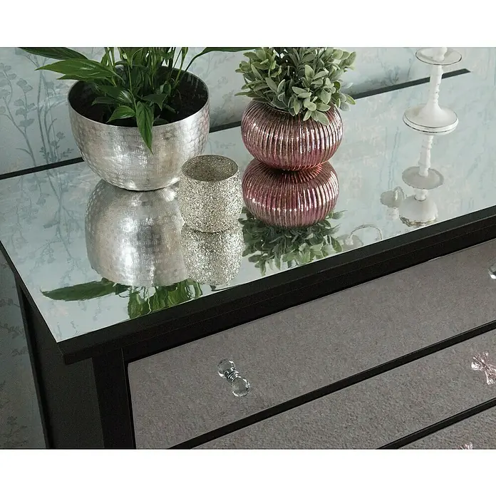 D-c-fix Klebefolie Spiegeleffektfolie - 120 x 90 cm, Spiegeleffekt, Selbstklebend - Ein Schrank mit Spiegelplatte, dekoriert mit Pflanzen, einem silbernen Teelichthalter und einer Kerzenleuchte.