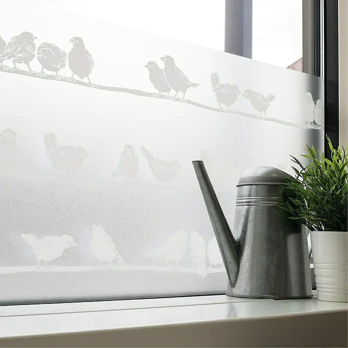 D-c-fix Static Premium Glasfolie Filippa - 150 x 45 cm, Transluzent, Statisch haftend - Fensterfolie mit Vogelmotiven auf einer Fensterbank mit einer Zinkgießkanne und einer Topfpflanze.