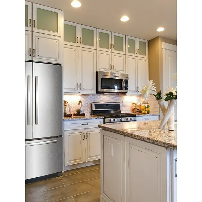 D-c-fix Metalleffektfolie Metallic Brush - 150 x 67,5 cm, Silber, Selbstklebend - Küchenansicht mit weißen Schränken, Edelstahlgeräten und einer Kücheninsel mit Granitplatte, die eine moderne und elegante Atmosphäre ausstrahlt.